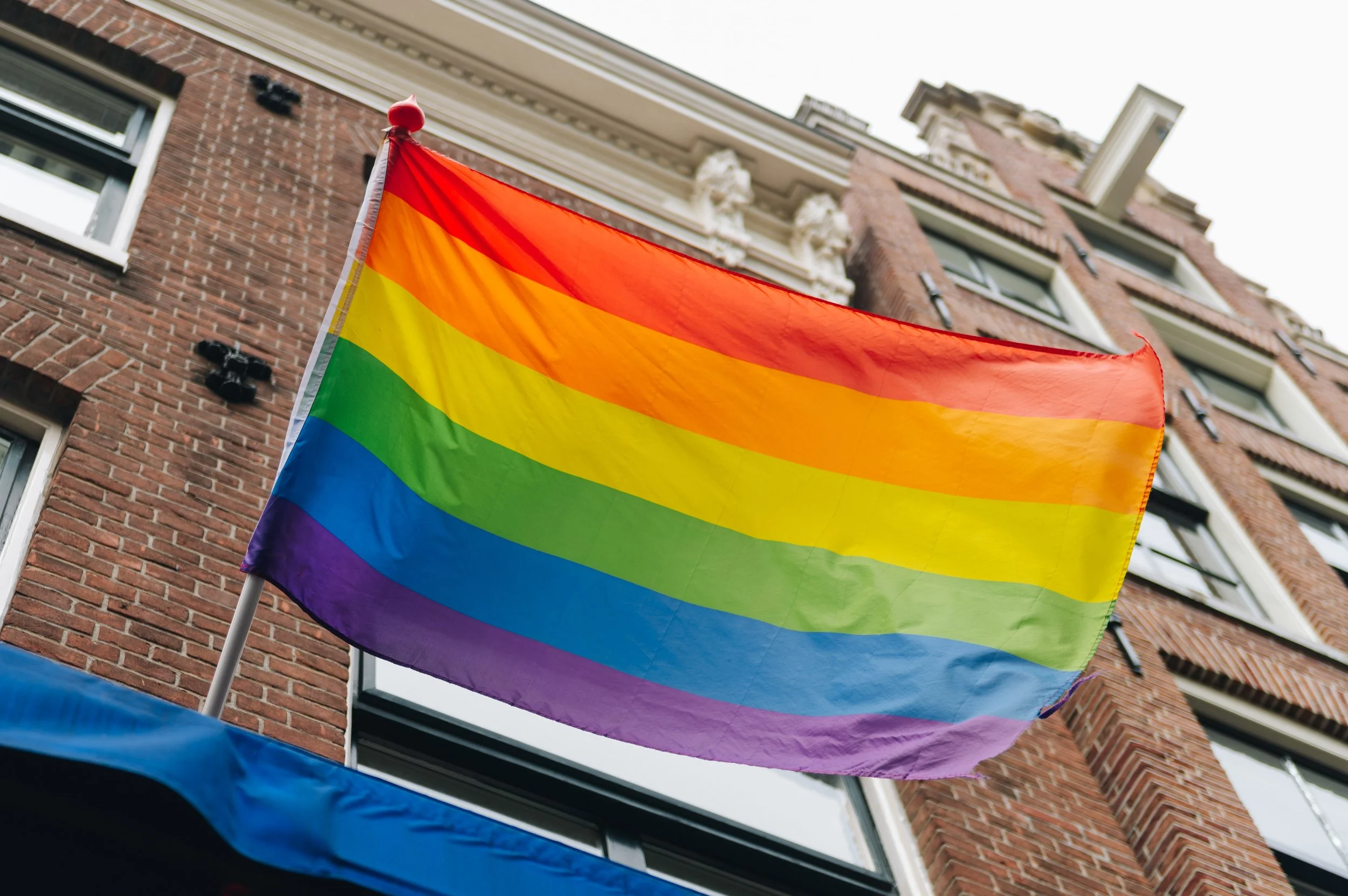 Rainbow flag also known as pride flag hanging outside of a building.