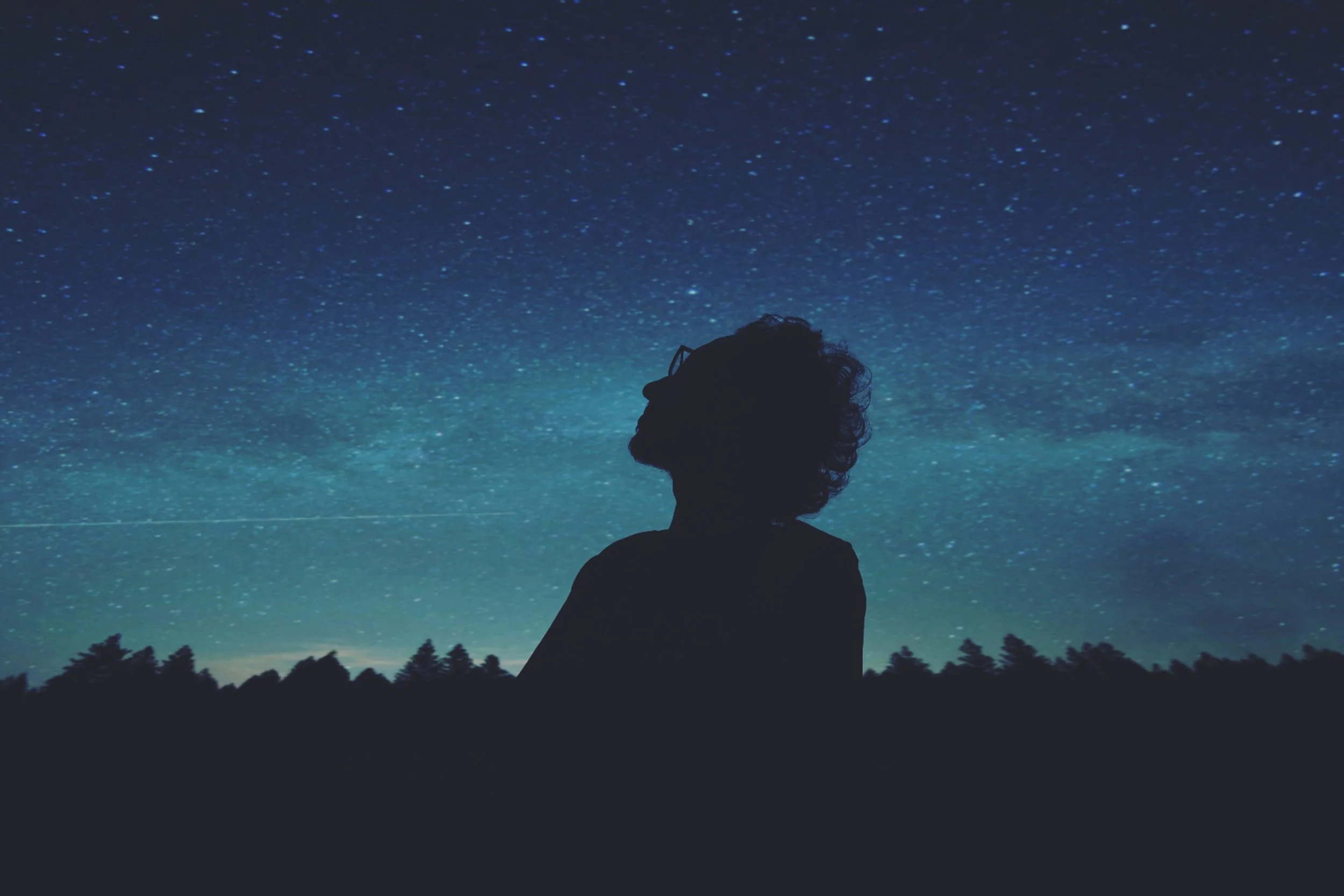  Person looking up at starry night sky.  